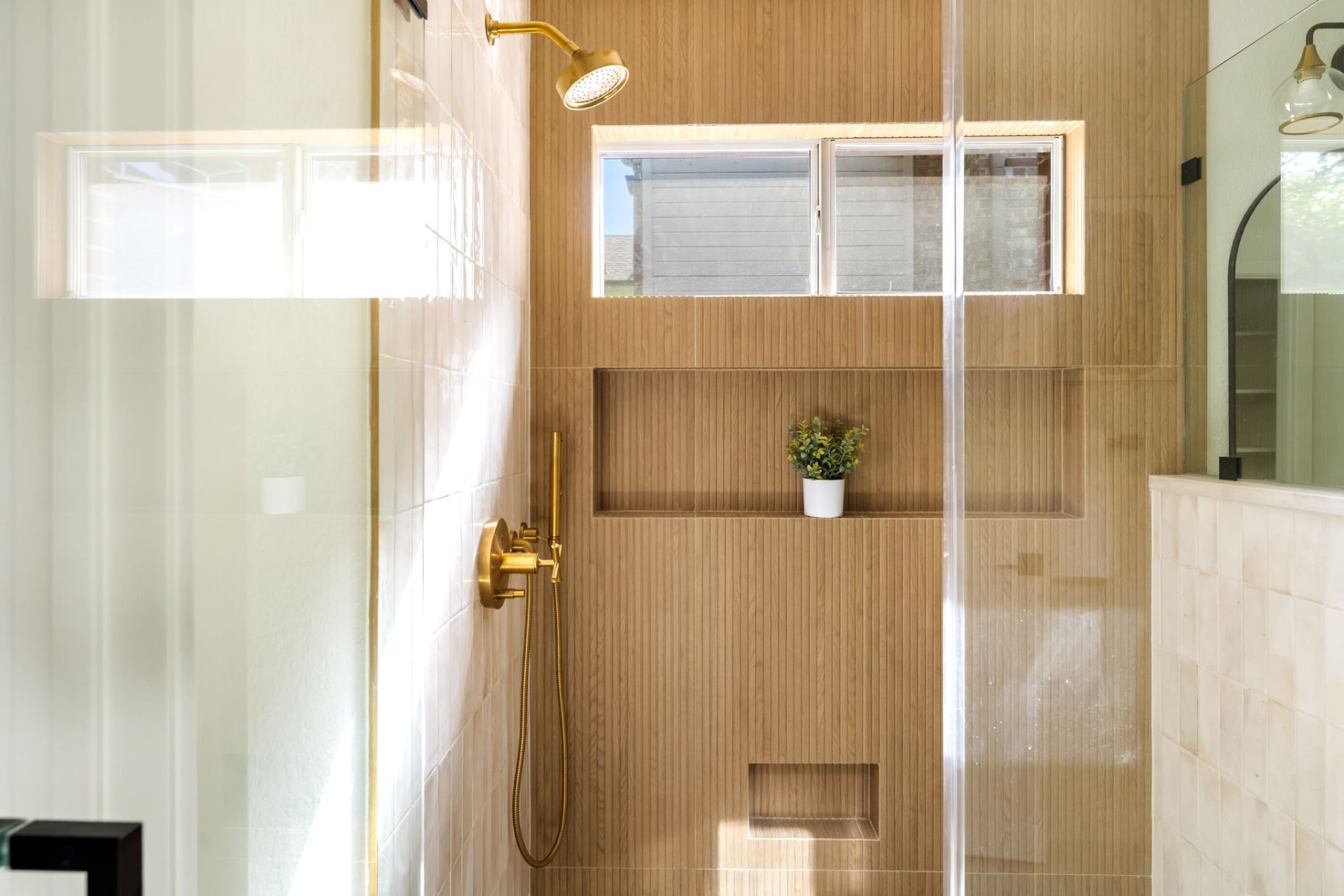 Gent Drive primary bath: walk-in glass shower with fluted wood-look tile and brass fixtures